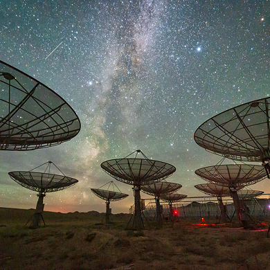 Radio telescopes under starry night sky.