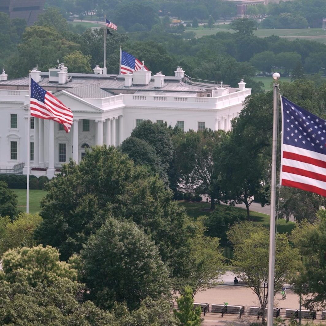White House with American flags flying outside.